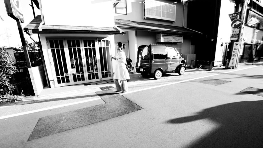 Black and white street scene with person and parked car